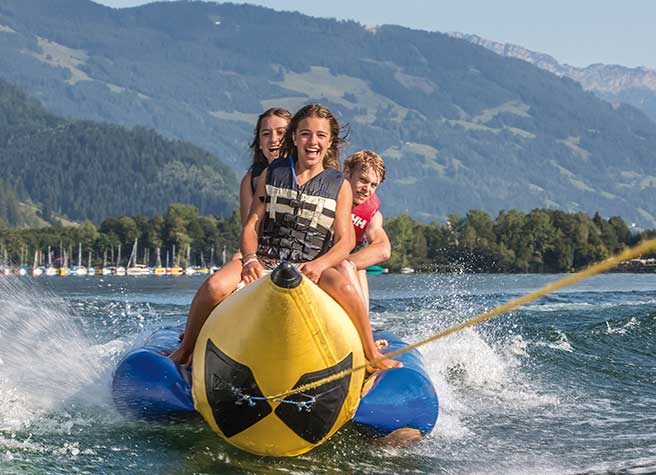 Familie auf einem Wassersportgerät, das auf einem See von einem Motorboot gezogen wird